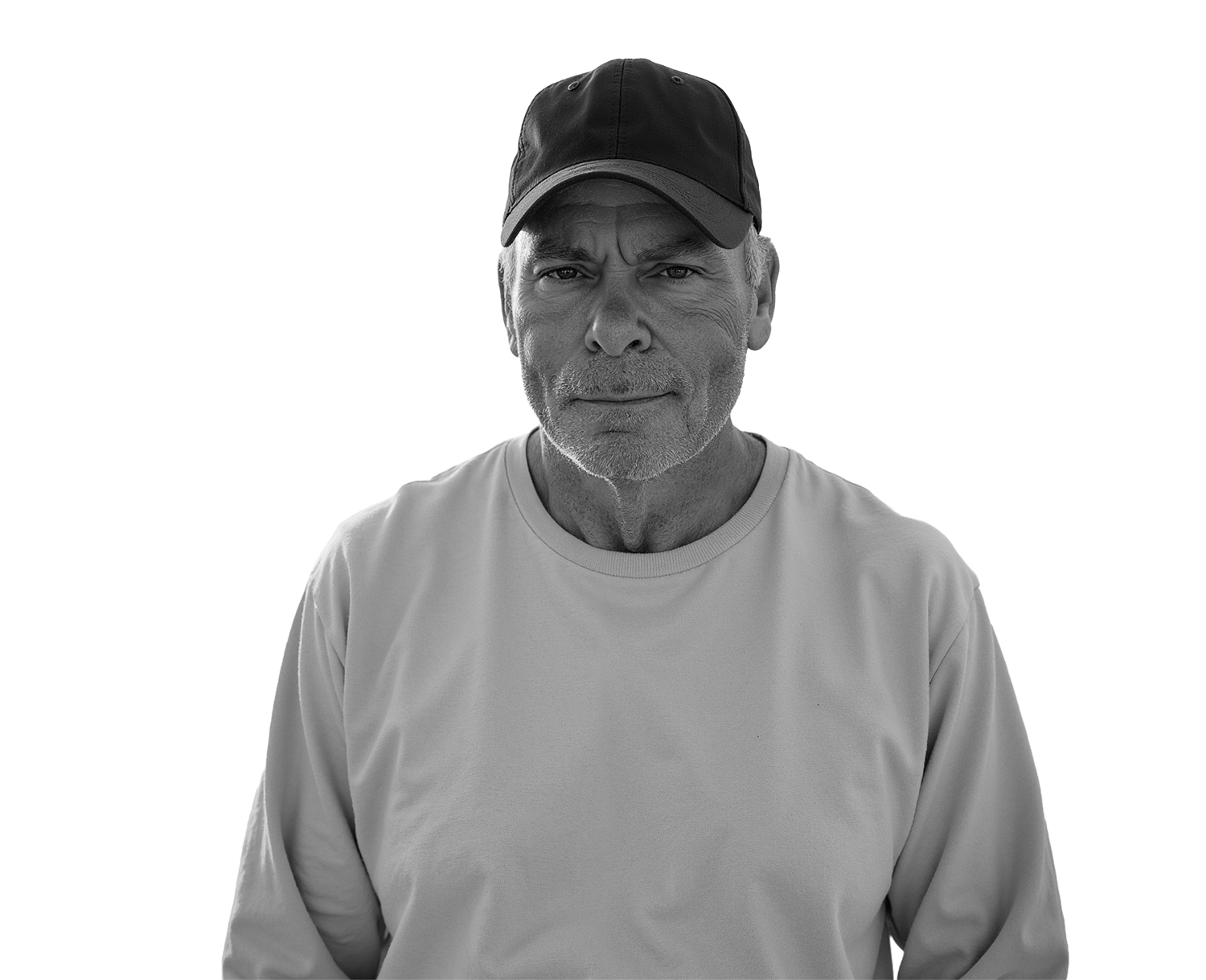 Man in a cap on a beach, black and white portrait with an ocean backdrop.